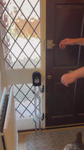 Lifting the locking bar and folding Dog Safety Gate Plus back at the front door